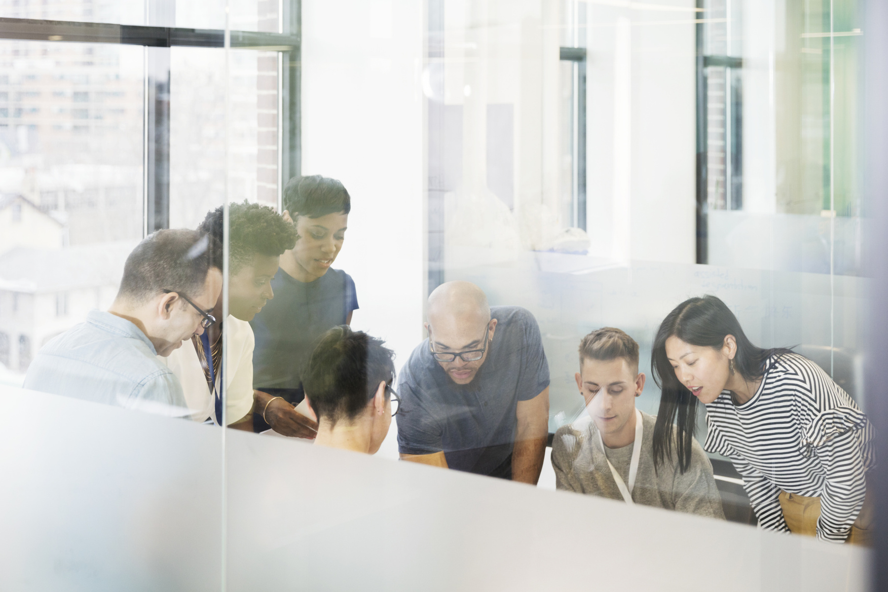 A team gathers around a table to work through a problem together.